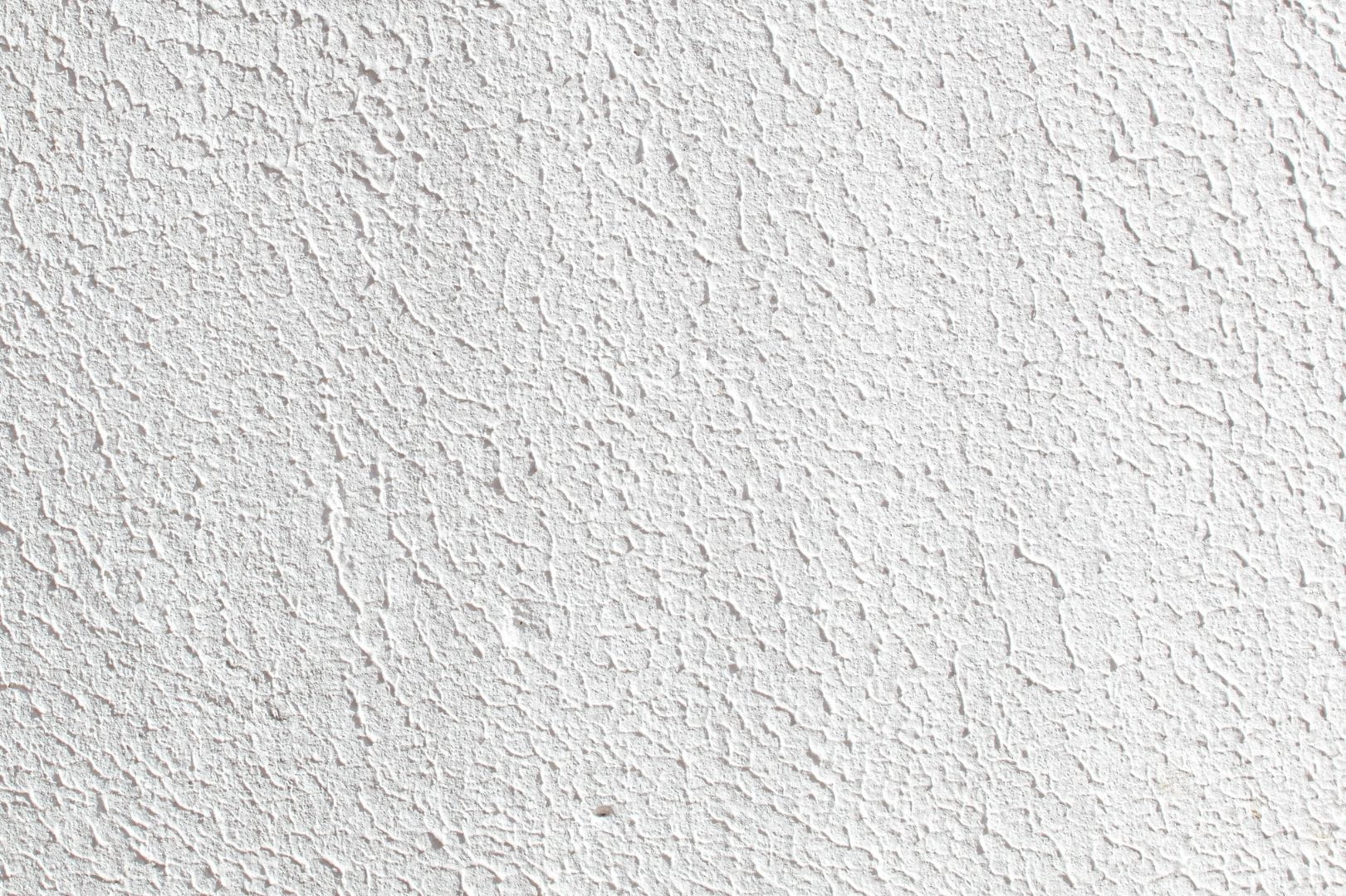 Gros plan sur la texture d'un crépi de façade finition grattée sur une maison à Dreux.