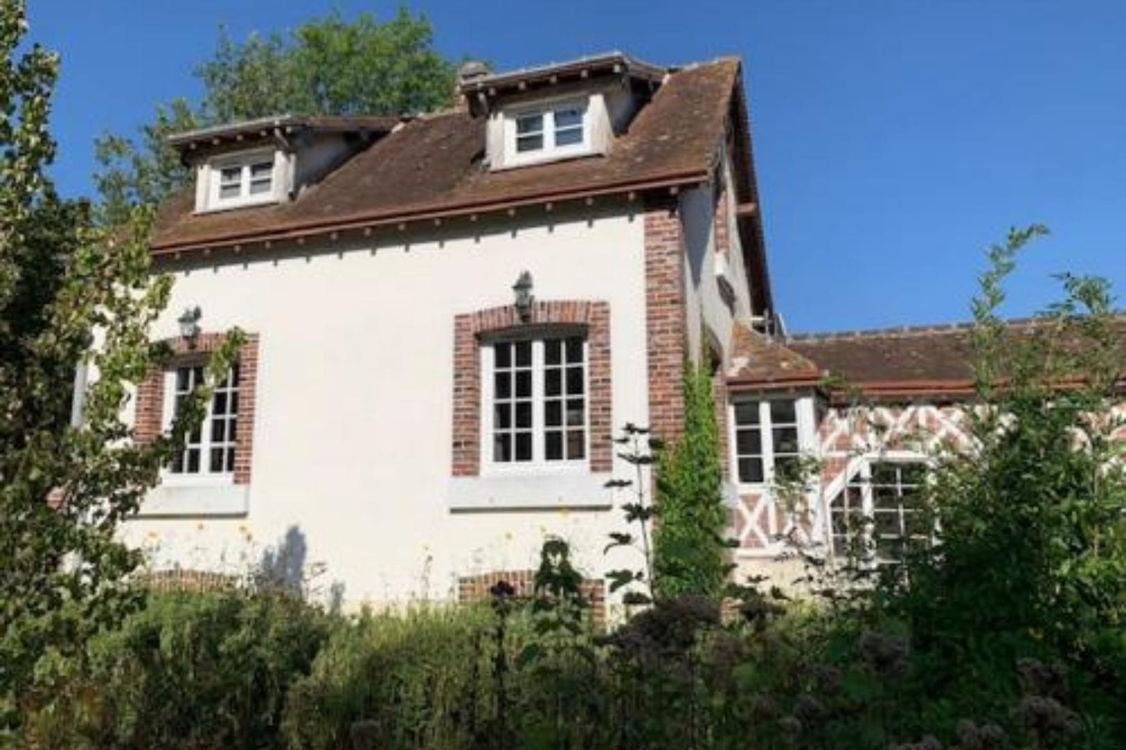 Maison traditionnelle rénovée à Charpont avec encadrements de fenêtres en briques rouges et lucarnes.