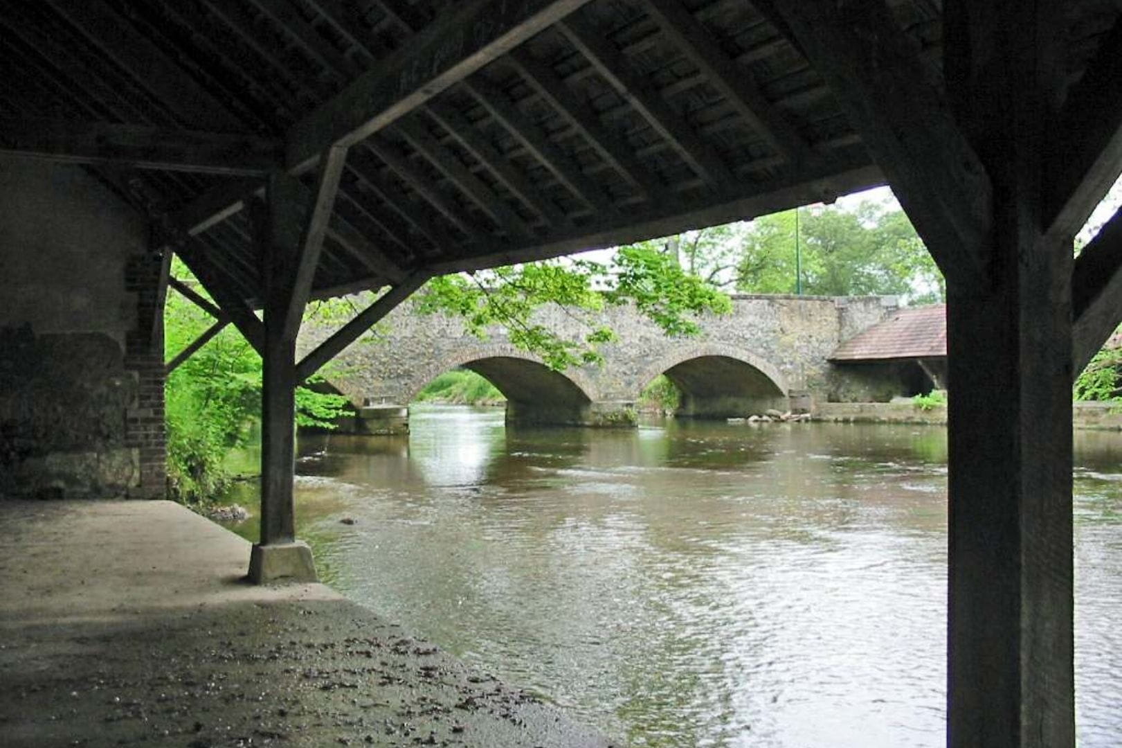 Vue pittoresque du pont en pierre de Garnay enjambant la rivière Eure, prise depuis l'ancien lavoir.