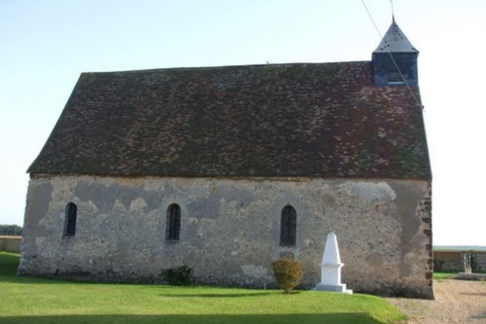 Église Saint-Lubin d'Allainville, petit édifice en pierre typique avec son monument commémoratif.