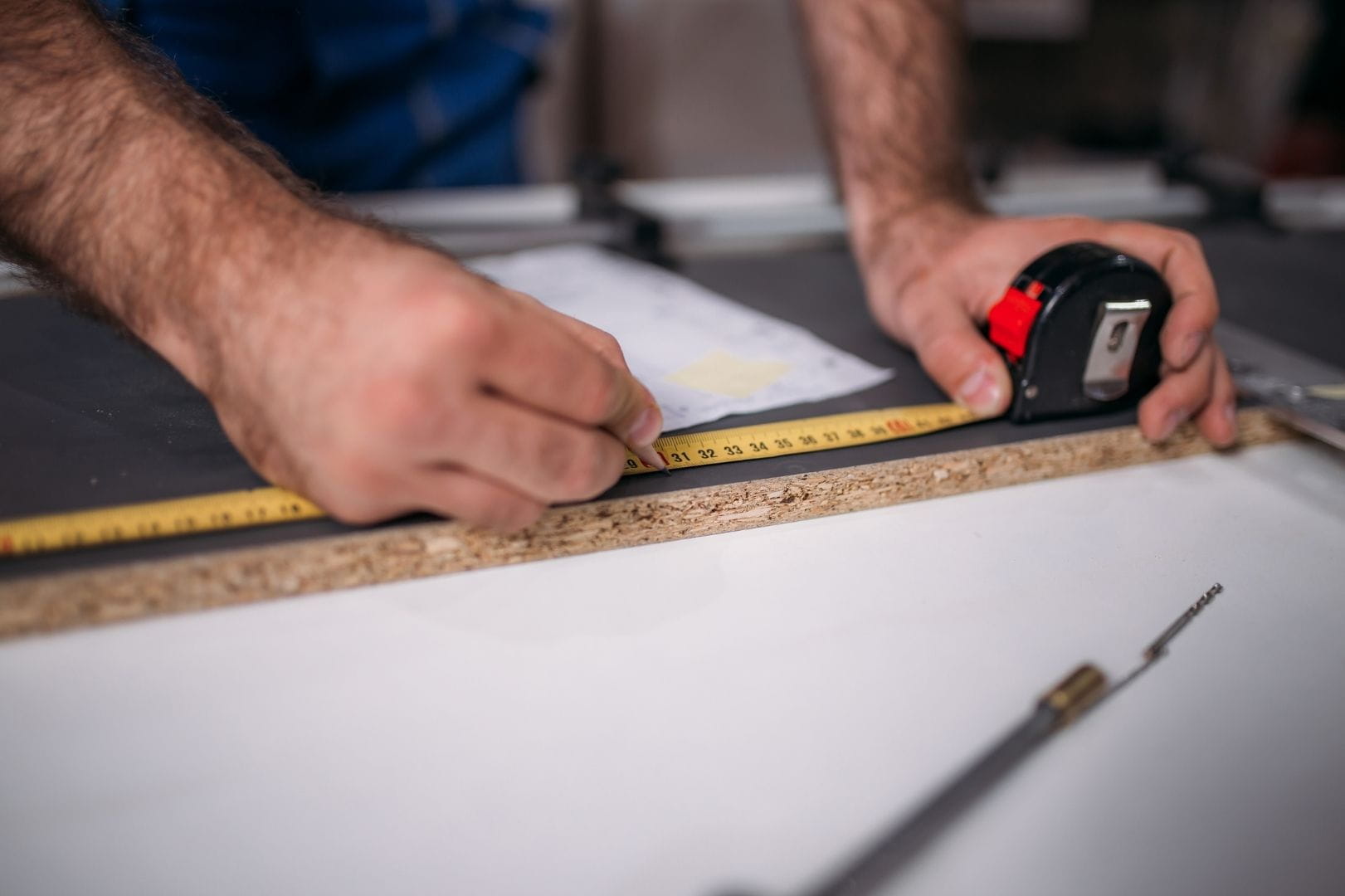 Prise de mesure précise au mètre ruban par un artisan lors de travaux d'aménagement à Dreux