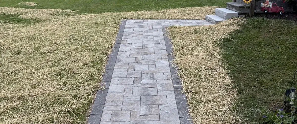 Paver walkway installation with fresh straw and lawn edging