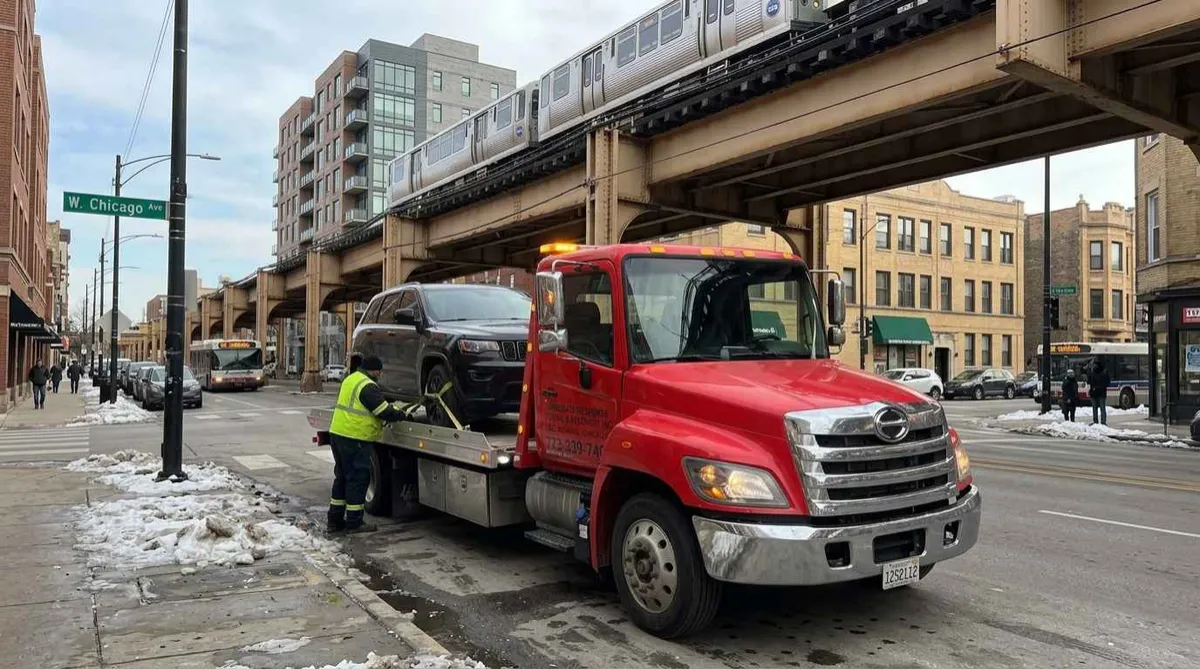 Flatbed tow truck loading a disabled sedan in Chicago's Loop neighborhood