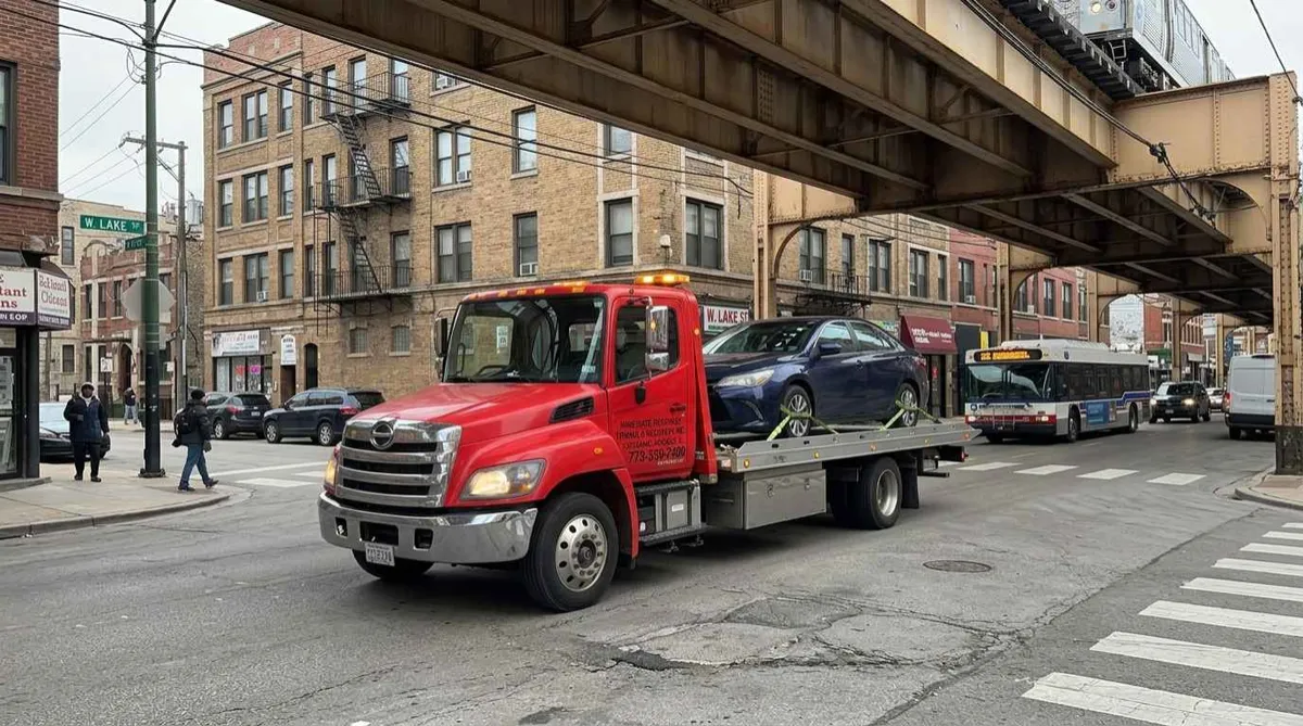 Light duty tow truck transporting a passenger car in Chicago