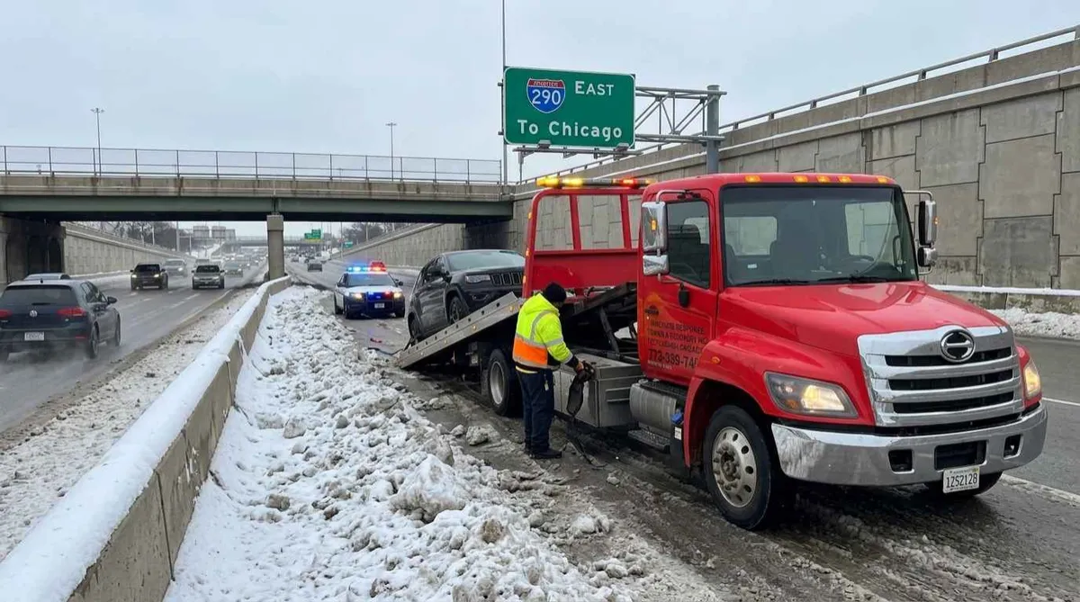 Emergency flatbed towing vehicle recovery on I-290 Eisenhower Expressway in winter"