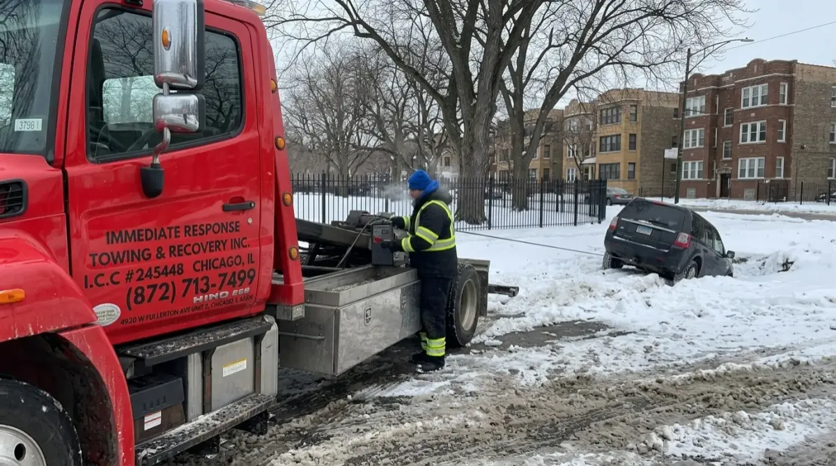 Tow truck performing winch recovery for stuck car