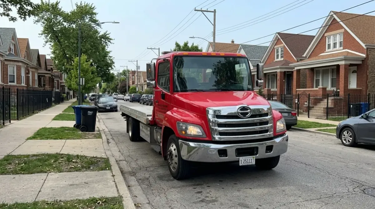 Tow truck navigating residential street with parked cars
