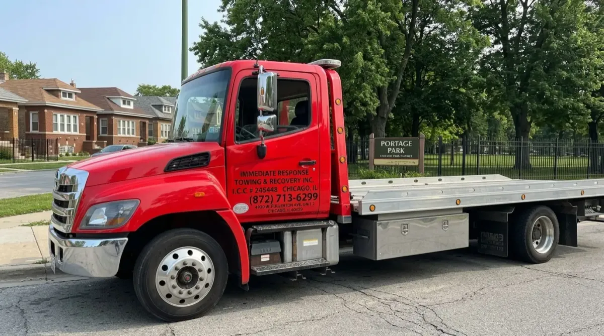 Tow truck parked on street surrounded by green space