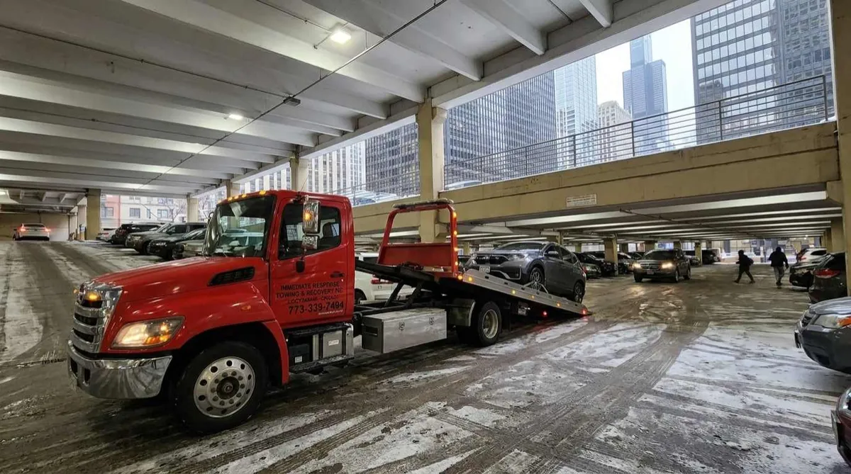 Flatbed tow truck serving a downtown Chicago parking garage