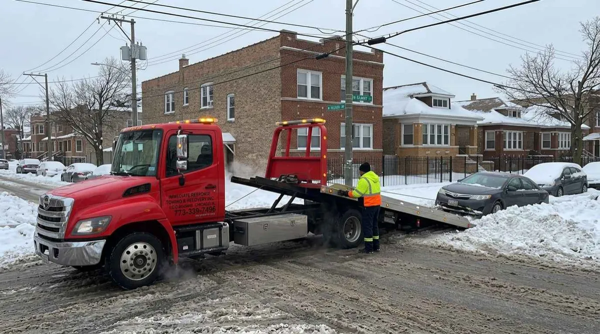 winch-out-snow-hermosa-chicago.webp / Alt: Tow truck pulling a car out of a snowbank on a Northwest Side Chicago street