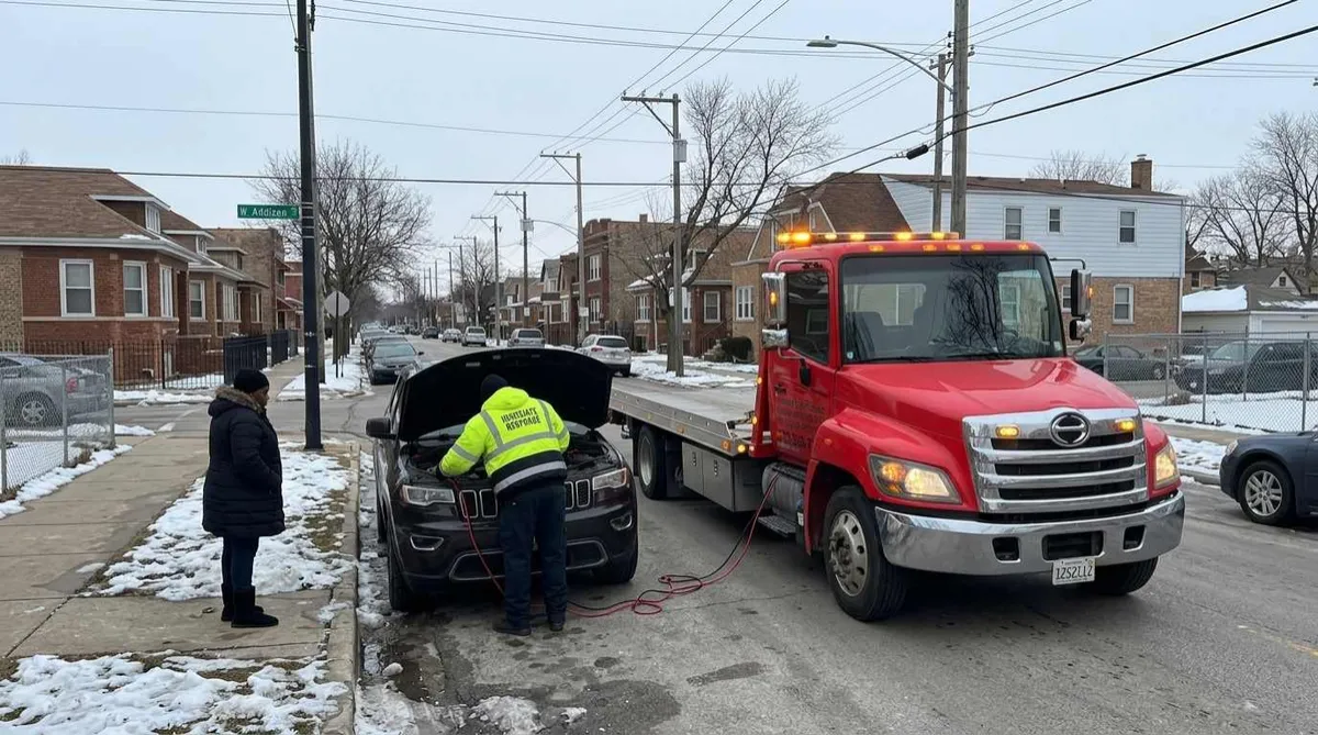 Technician jump starting a dead battery on a Dunning Chicago street