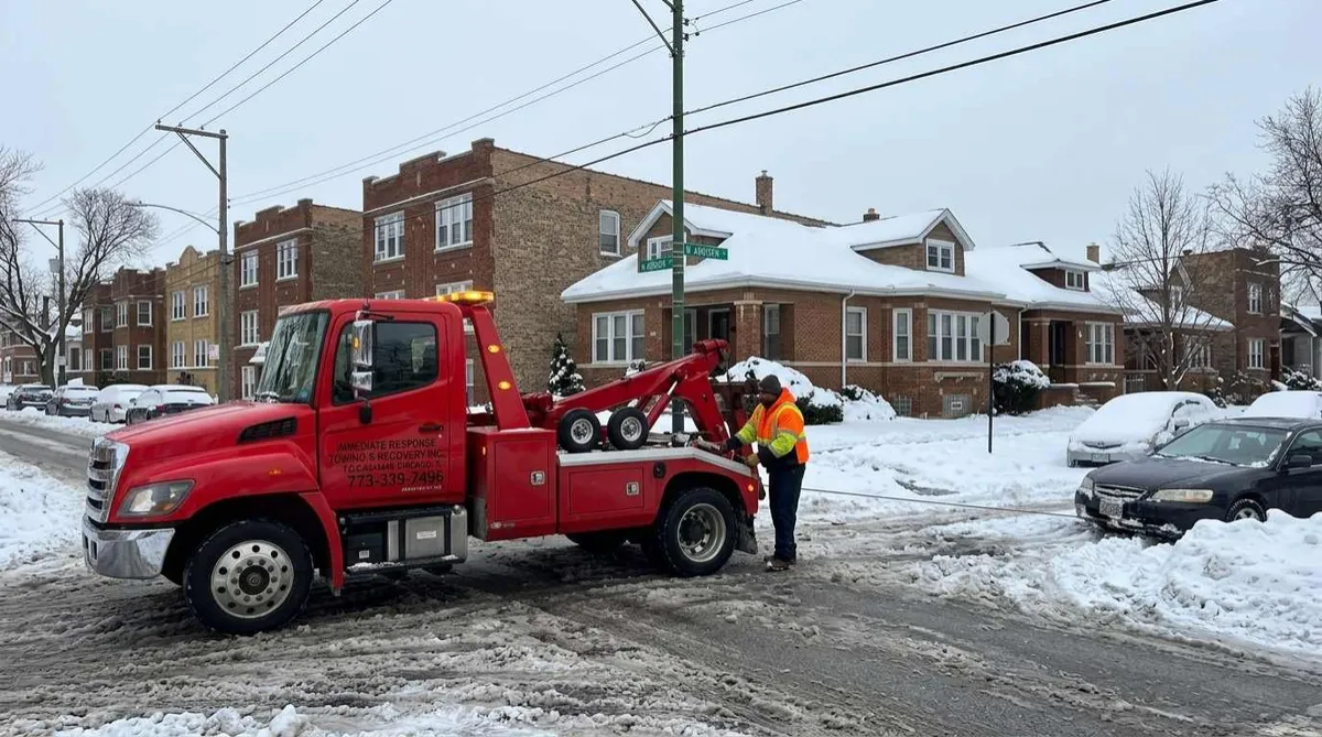 Tow truck pulling a car out of snow on a Northwest Side Chicago street