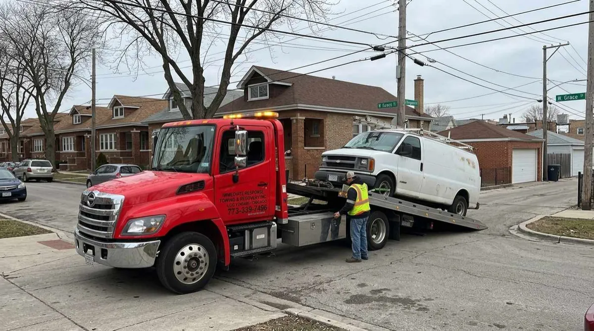 Flatbed tow truck loading a work van for safe vehicle transport in Dunning, Chicago