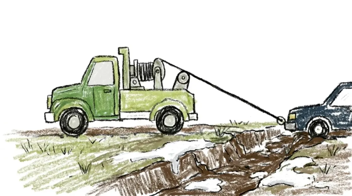 Tow truck pulling stuck car from a snowbank and ditch using a winch