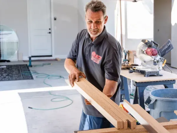 Professional installer applying epoxy floor coating along the edge of a concrete surface during the installation process.