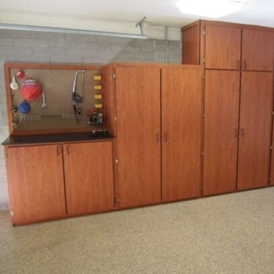 s a well-organized garage  of wooden cabinets and a pegboard