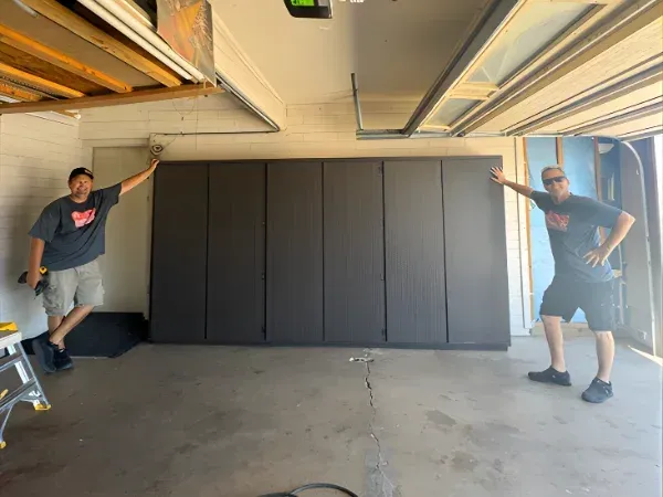 Garage cabinet installation team showing completed custom storage wall in garage