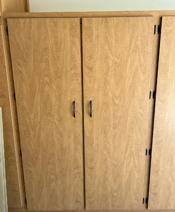A close-up shot of light-colored wood cabinets, two of which have sleek black pull handles.