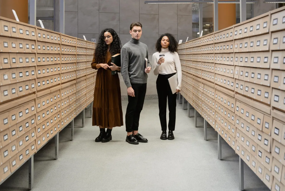 people standing in an aisle of library card catalogs