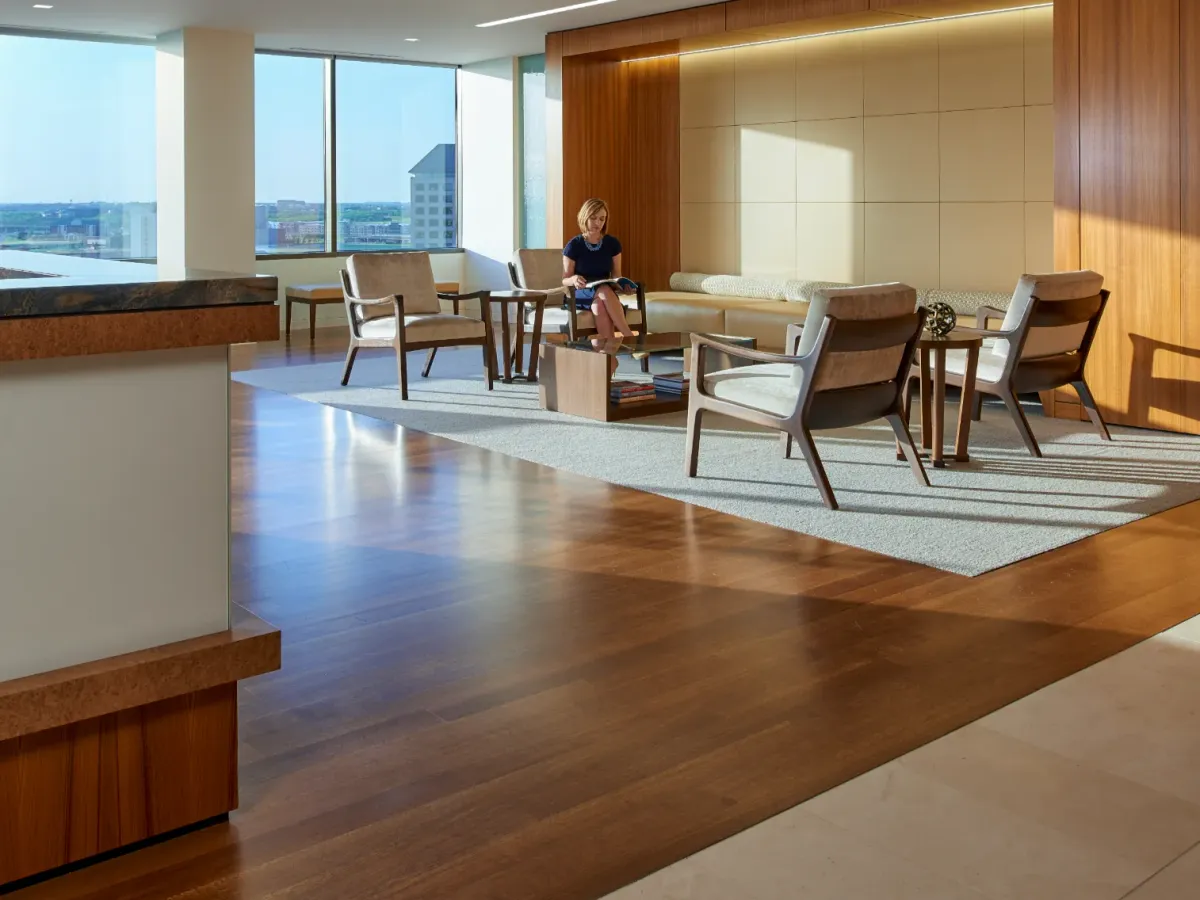 The image shows a woman sitting on a chair. She is surrounded by furniture.