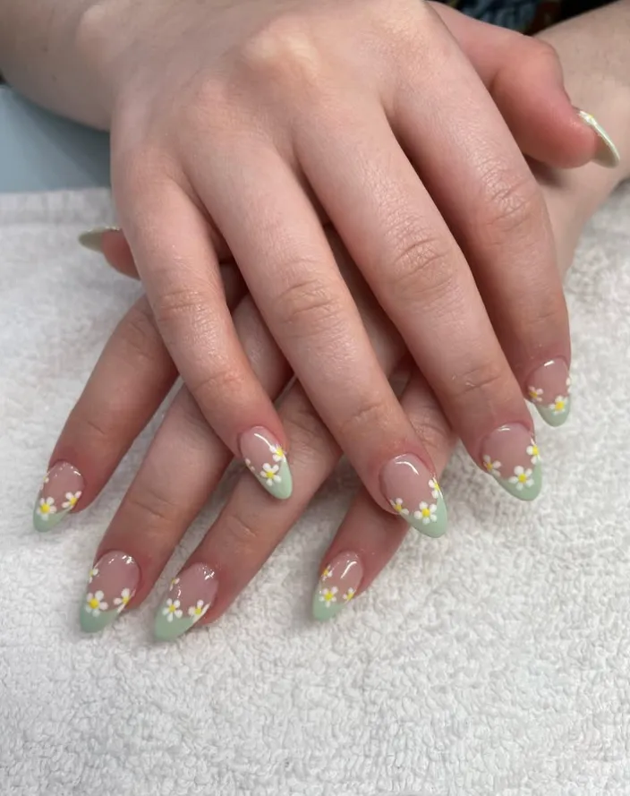 A young professional woman typing on a laptop, her hands displaying a sleek, minimalist gel manicure in soft pink. The modern workspace includes a coffee cup and notepad, emphasizing style and productivity.
