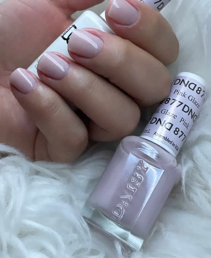 A close-up of a hand with intricate pastel floral nail art, gently holding a white teacup. The background is softly blurred, drawing attention to the detailed, artistic nail design and the delicate, feminine style.