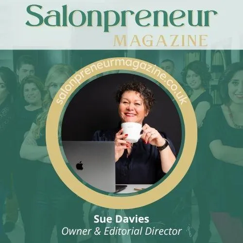 Sue Davies, Founder & Editorial Director of Salonpreneur Magazine. Sue wears black shirt, and holds white cup in both hands wearing red nail polish. Dark hair, minimal make up with red lipstick. Sitting desk facing camera with open laptop. Subscribe at  www.salonpreneurmagazine.co.uk