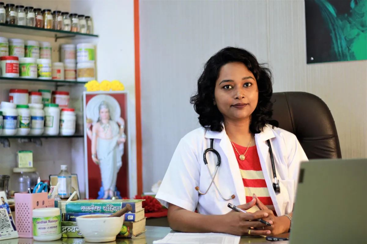 Portrait of Dr Lummbini, early-40s female cosmetic coach, warm natural light, seated at a minimalist desk with botanical jars blurred in background — photorealistic, elegant feminine styling emphasizing trust and expertise.