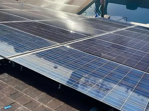 A row of solar panels being cleaned, reflecting sunlight as they are washed for improved efficiency.