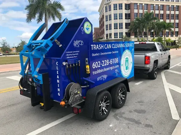 Blue trash can cleaning truck with professional branding, parked in an urban area.