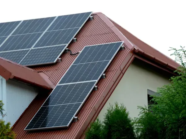 A house with a red-tiled roof featuring multiple solar panels cleaned for efficient renewable energy use.