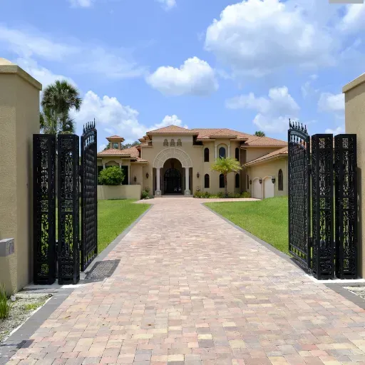 Modern driveway with stone pavers, illuminated by path lighting, leading to a contemporary home surrounded by trees.