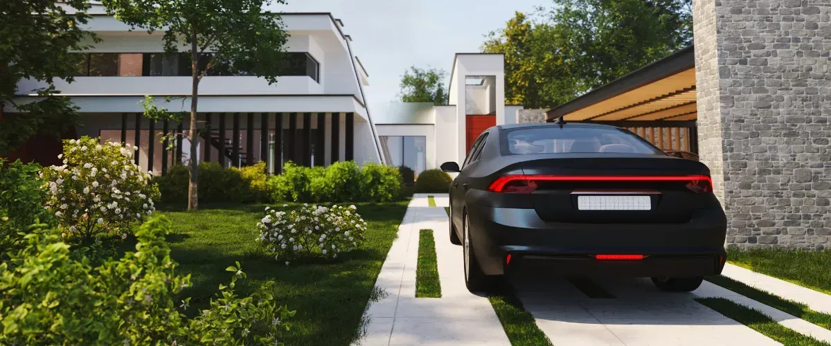 Residential driveway with a beige garage door, stone accents, and a wooden fence surrounding the lawn