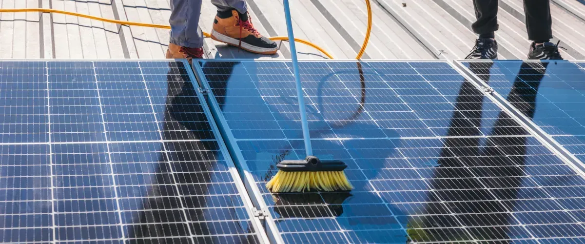 man cleaning solar panelon a roof