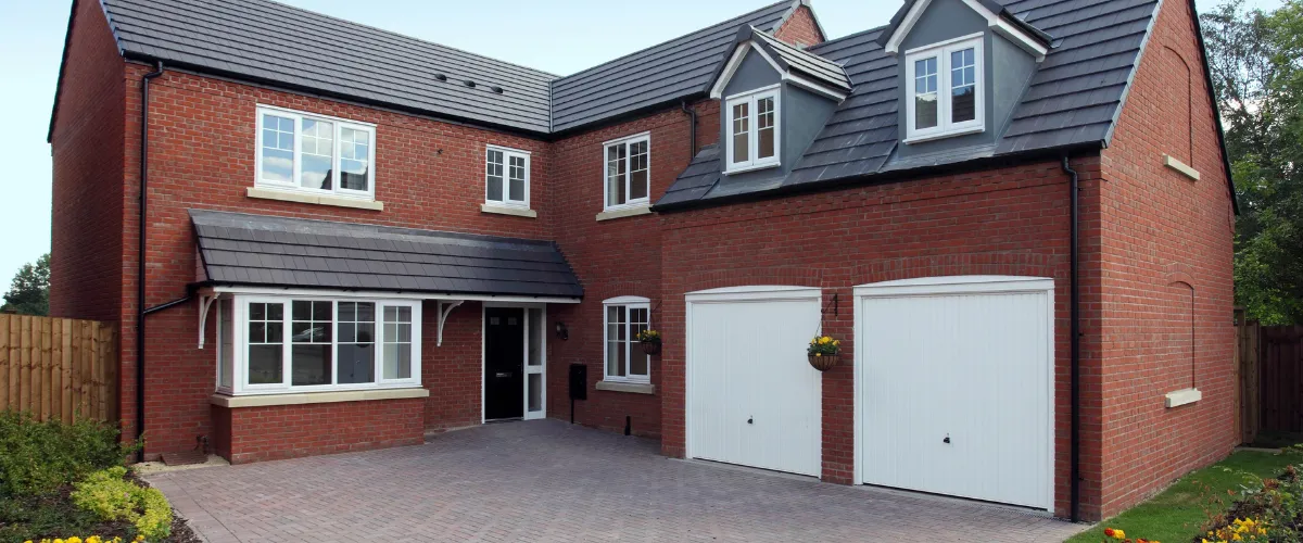 Red brick house with twin white garage doors and a paved driveway