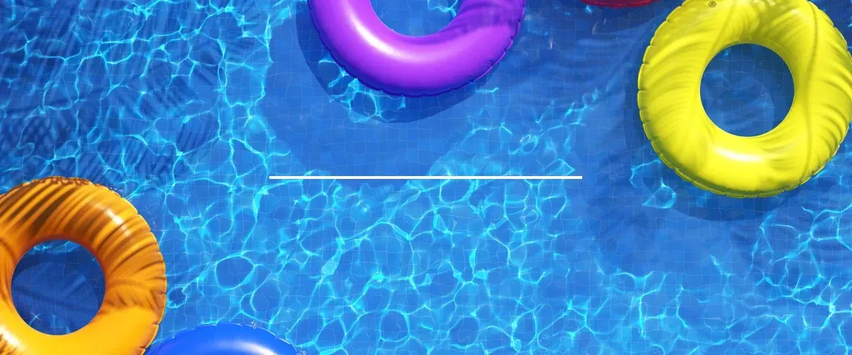 Colorful inflatable float rings floating in a bright blue swimming pool on a sunny summer day.