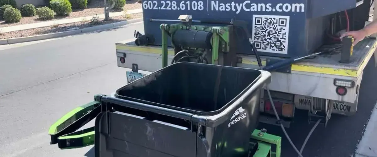 Trash bin cleaning truck with black bin labeled Mesa AZ being serviced 