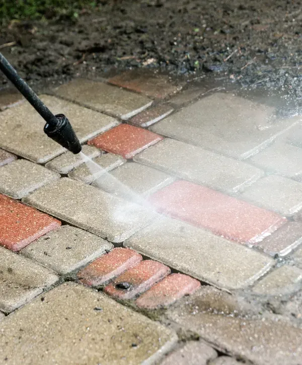 Professional pressure washing service cleaning a brick driveway to remove dirt and stains.