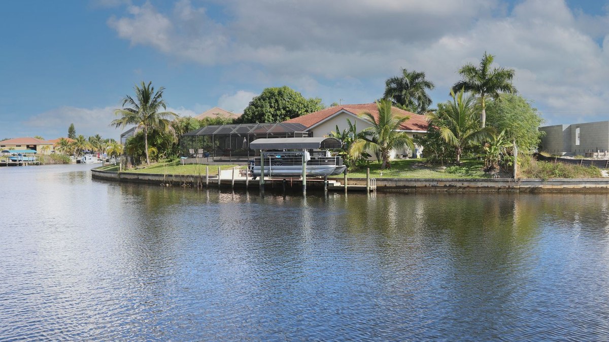 One-story stucco home with tile roof and boat lift on a gulf-access canal in Cape Coral, Florida