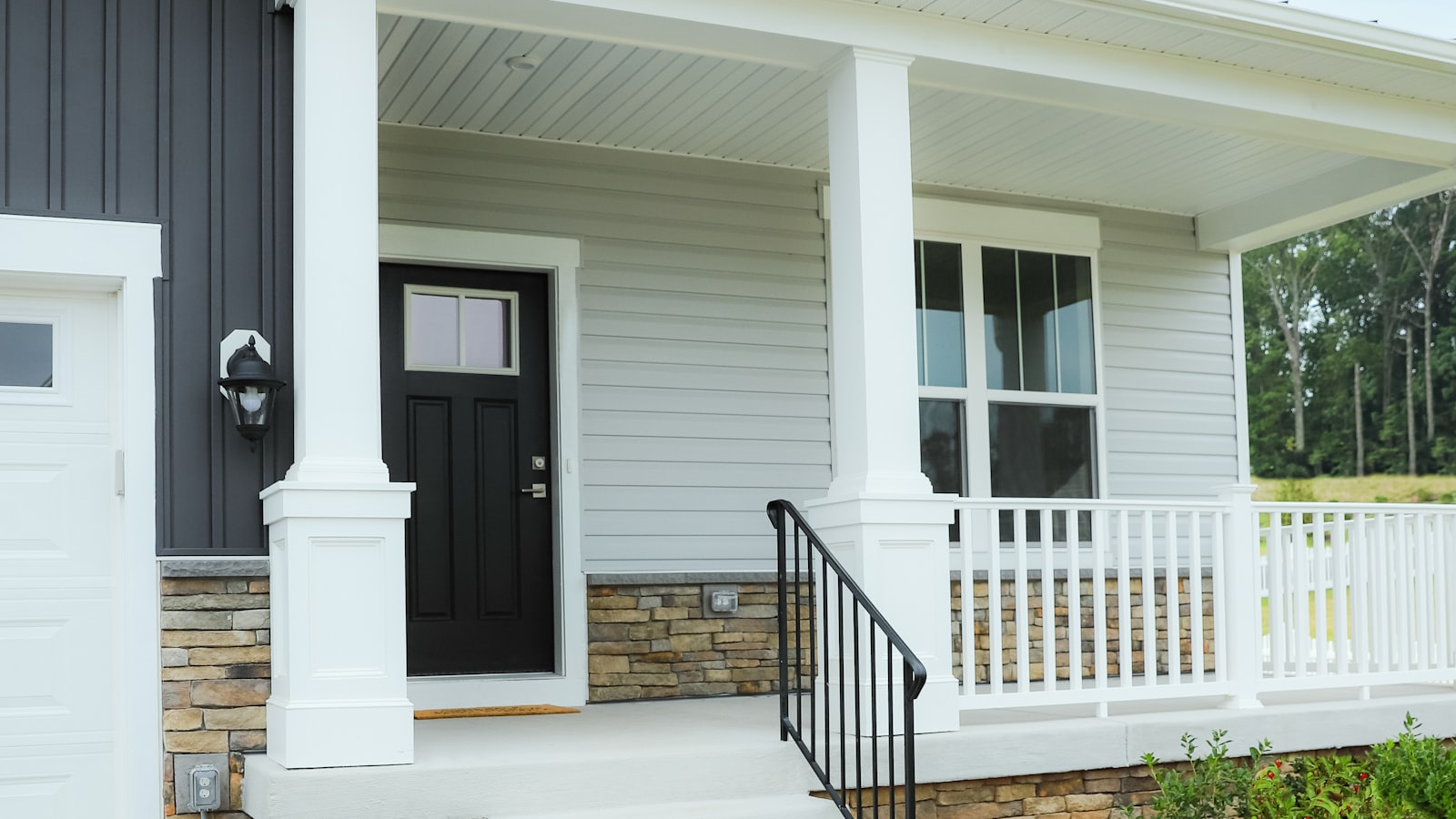 Front porch and entry of a newly built home with stone accents and white columns