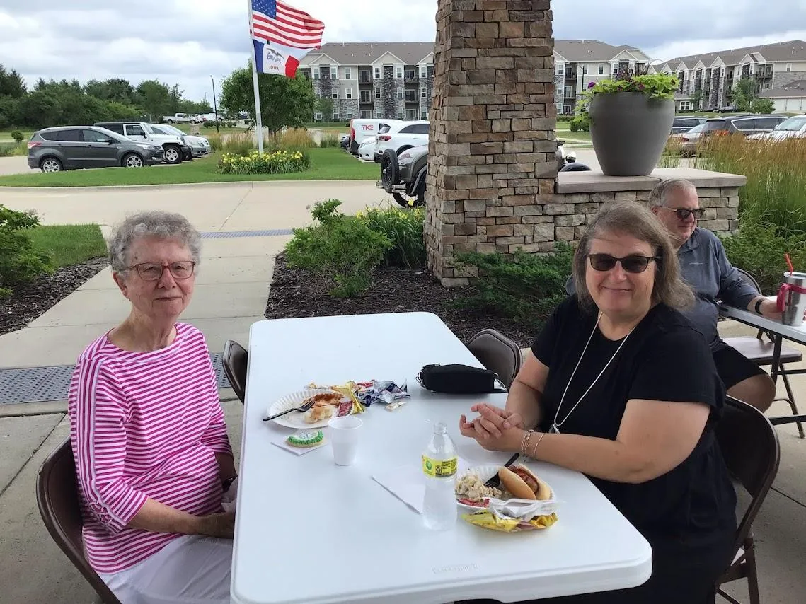 Grassy marshland with forested hills under blue sky.