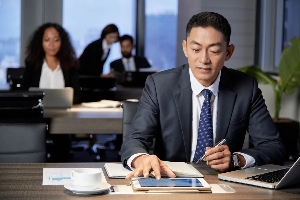 Business consultant reviewing insights on a tablet in a modern office, supporting executive advisory and strategic decision-making.