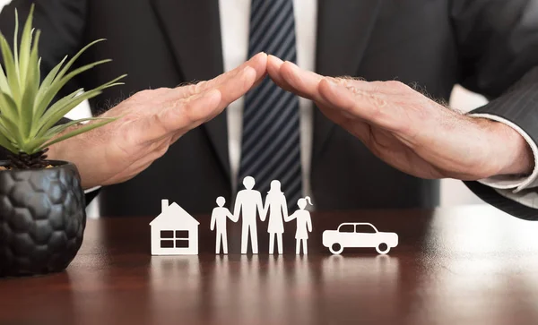 insurance agent holding hands over a paper family as if to protect them