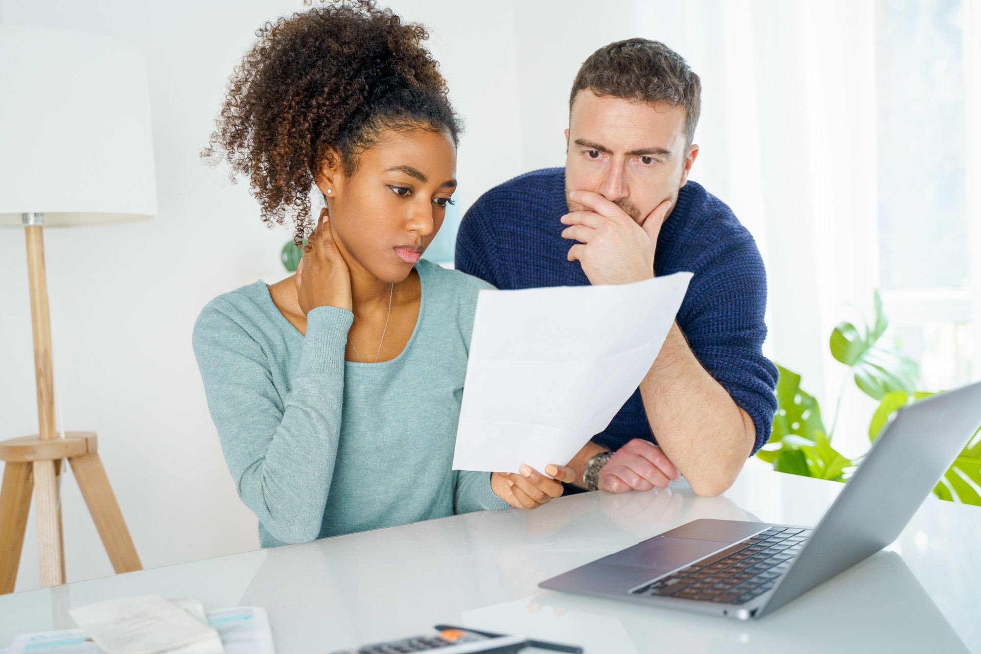 A clean, modern 3:2 image of a professional financial advisor, mid-30s, meeting with a young couple in a bright office. The advisor gestures to a digital tablet displaying charts, while the couple listens attentively. The setting is contemporary, with soft neutral tones and large windows.