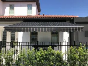 Homeowner using remote to extend motorized awning over patio