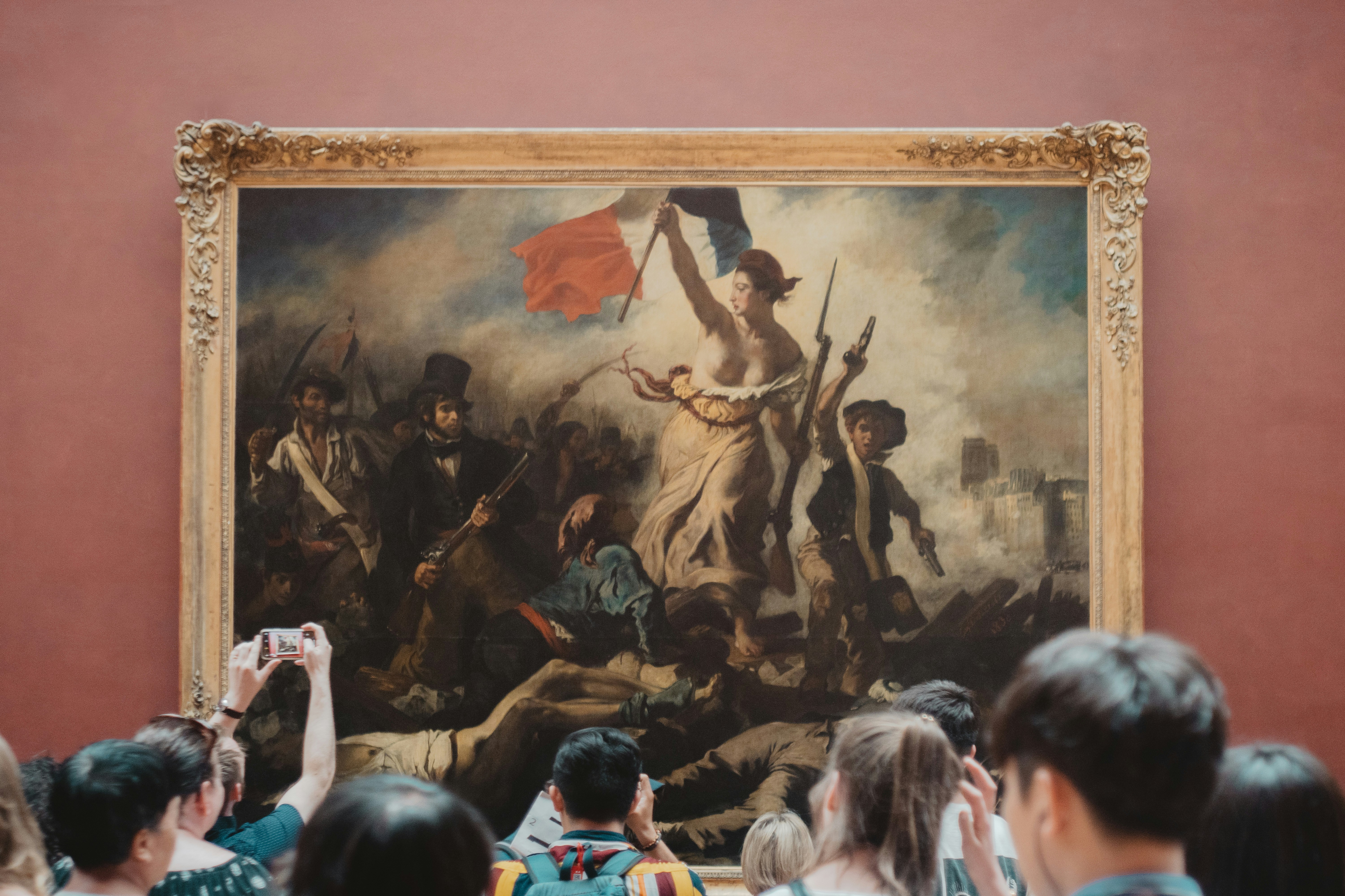 Visitors viewing Eugène Delacroix’s “Liberty Leading the People” at the Louvre Museum in Paris, symbolizing the history and culture explored through educational travel in Europe.