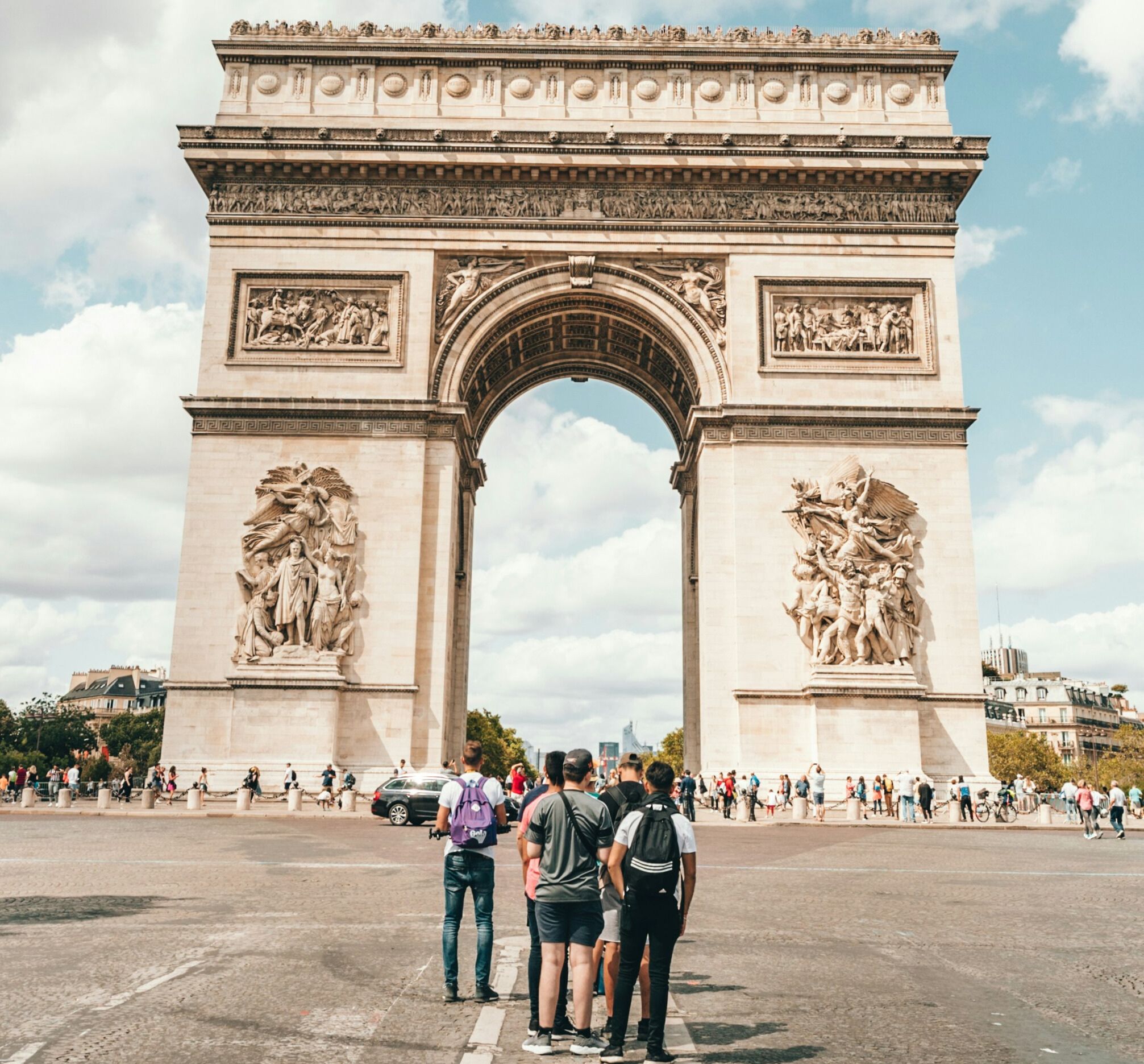 Travelers standing beneath the Arc de Triomphe in Paris, a historic monument connected to Napoleon and European history.