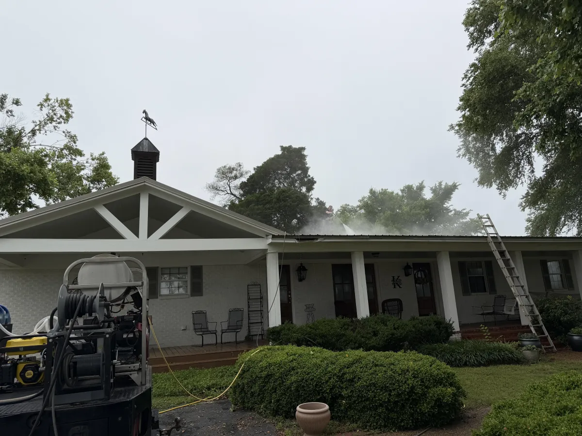 Professional metal roof cleaning in Ripley with a technician washing the roof of a residential home.