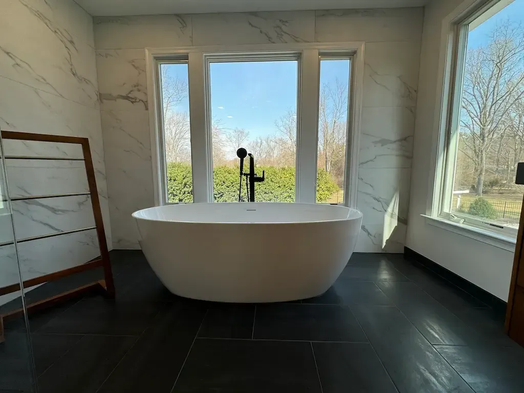 Oakton Virginia freestanding soaking tub and double floating vanity in primary bathroom suite with separate water closet