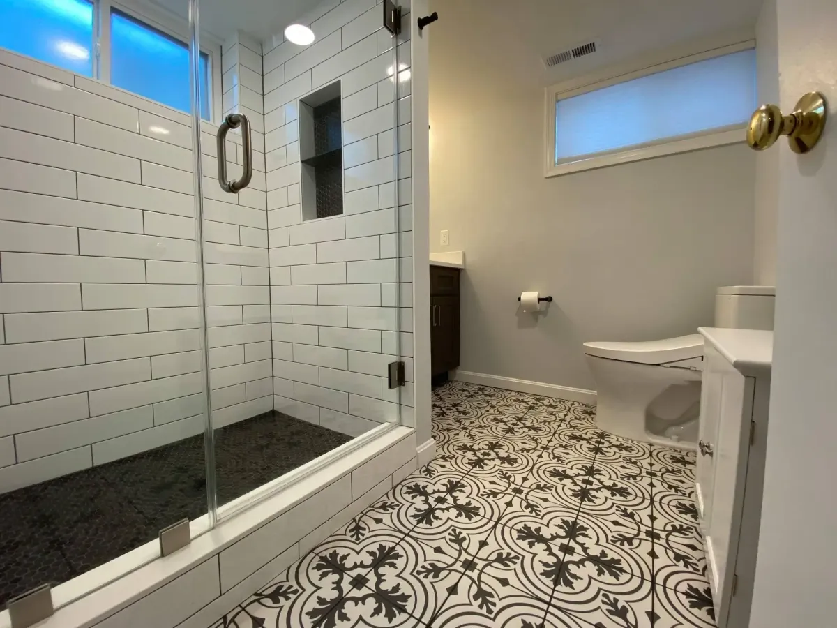 New Arlington basement bathroom with walk-in shower, patterned tile floor, and custom vanity built around structural column